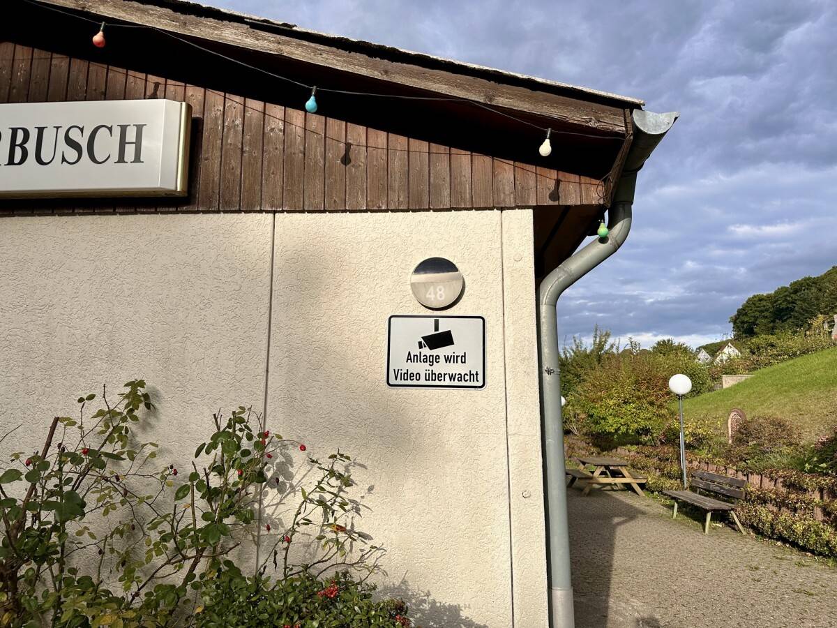 Hinweisschild zur Videoüberwachung als Abschreckung gegen Einbrüche im Kleingarten Warnschild mit Kamera-Symbol und Aufschrift „Achtung! Grundstück wird videoüberwacht!“ am Zaun