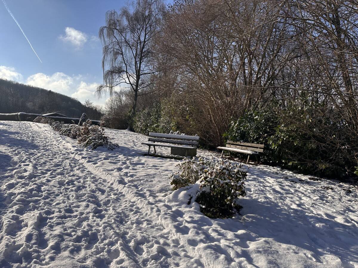 Sitzbank am Weg im Winter Verschneite Sitzbank neben einem Weg im Kleingärtnerverein Westerbusch