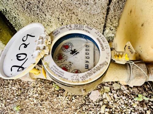 Wasserzähler im Garten mit gelber Plombe und handschriftlicher Jahresmarkierung 2025